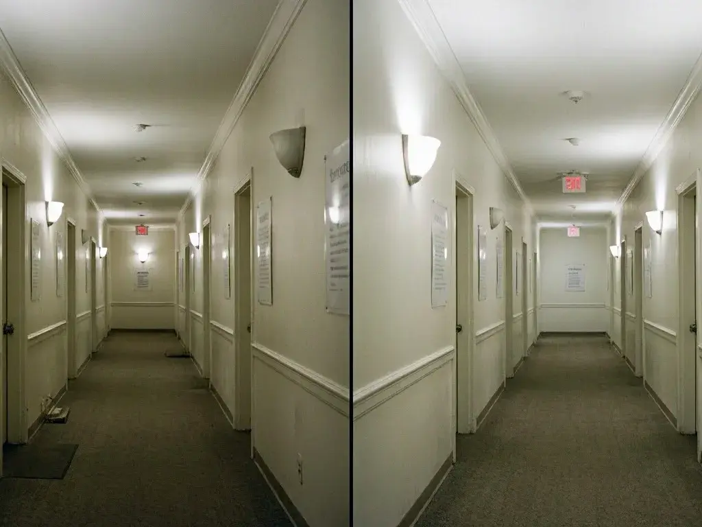 Narrow apartment hallway with white walls, closed doors, wall lights, and