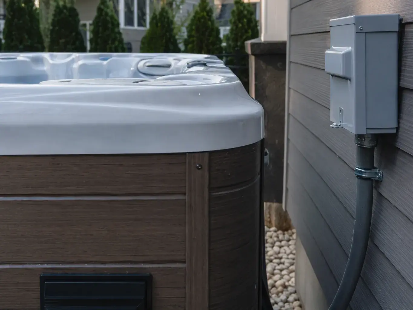 Hot tub beside a house wall with electrical box and conduit attached
