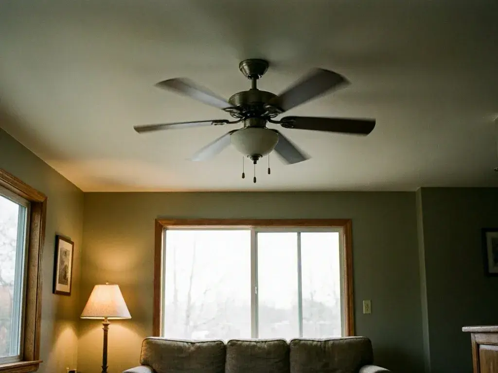 Bright living room with a lit floor lamp, sofa, window, and spinning ceiling fan